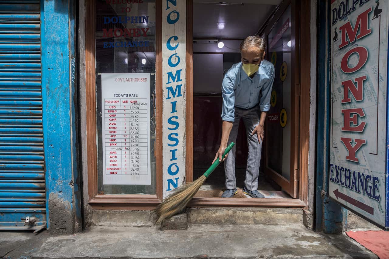 A man wears a mask as he cleans his money exchange shop at Thamel, a major tourist hub, after government ended the COVID-19 coronavirus lockdown in Kathmandu, Nepal, 22 July 2020. 