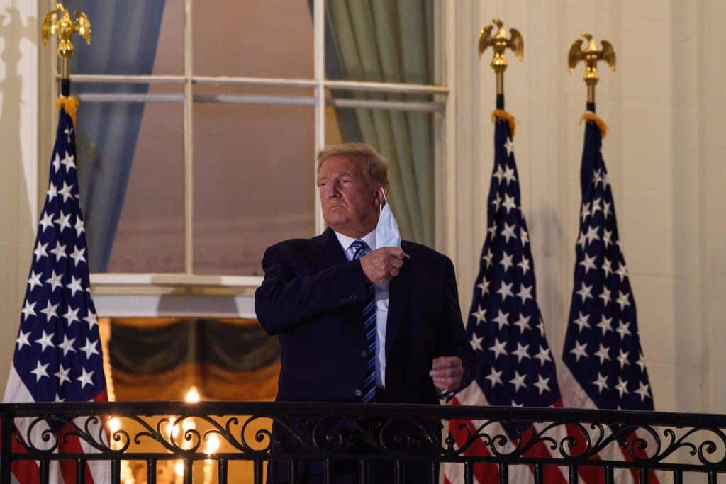 US President Donald Trump takes off his mask as he arrives at the White House upon his return from Walter Reed Medical Center