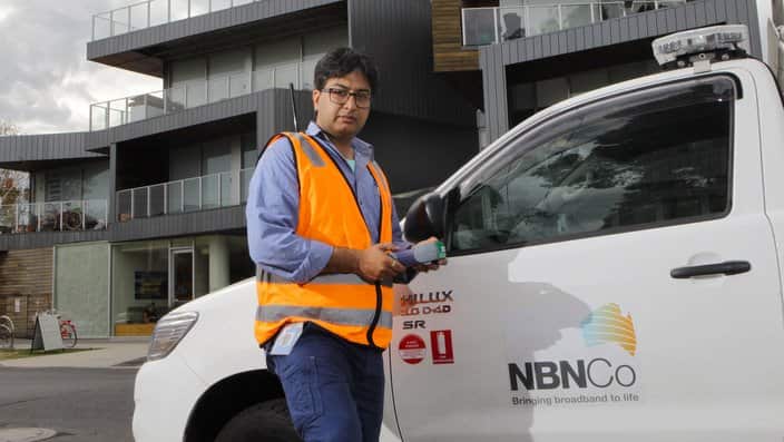 NBN technician in front of an aparthament block that s been connected to the National Broadband Network