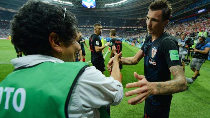 Mario Mandzukic (R) of Croatia helps up photographer Yuri Cortez after he was knocked off his seat