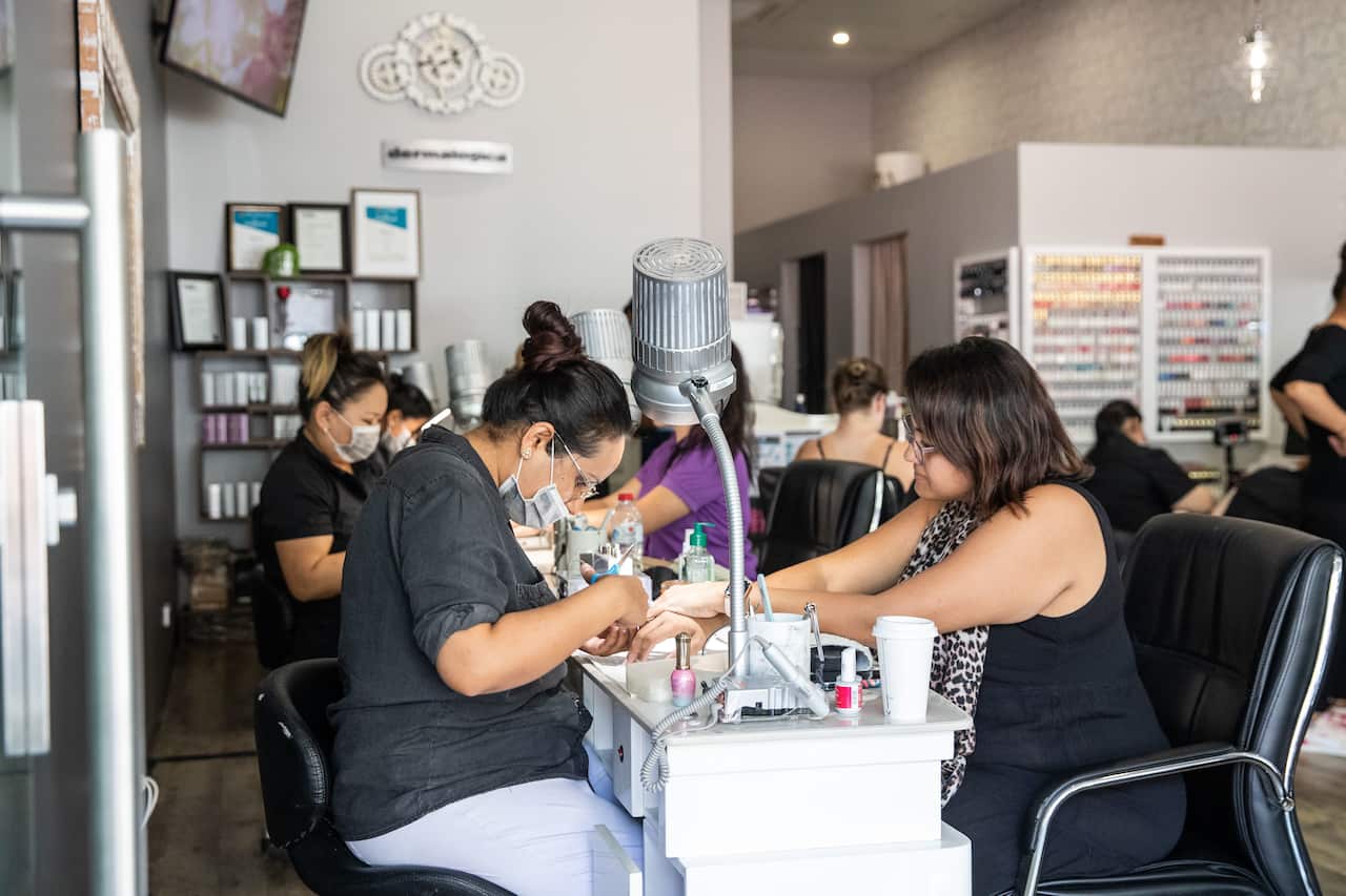 Cre8tive Nails owner Rosie Thind with customer in Darwin, Friday, May 15, 2020. The Northern Territory has lifted a range of restrictions but social distancing is still required. (AAP Image/Helen Orr) NO ARCHIVING