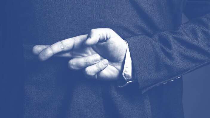 Dishonest businessman telling lies, lying businessperson holding fingers crossed behind his back (Igor Stevanovic)