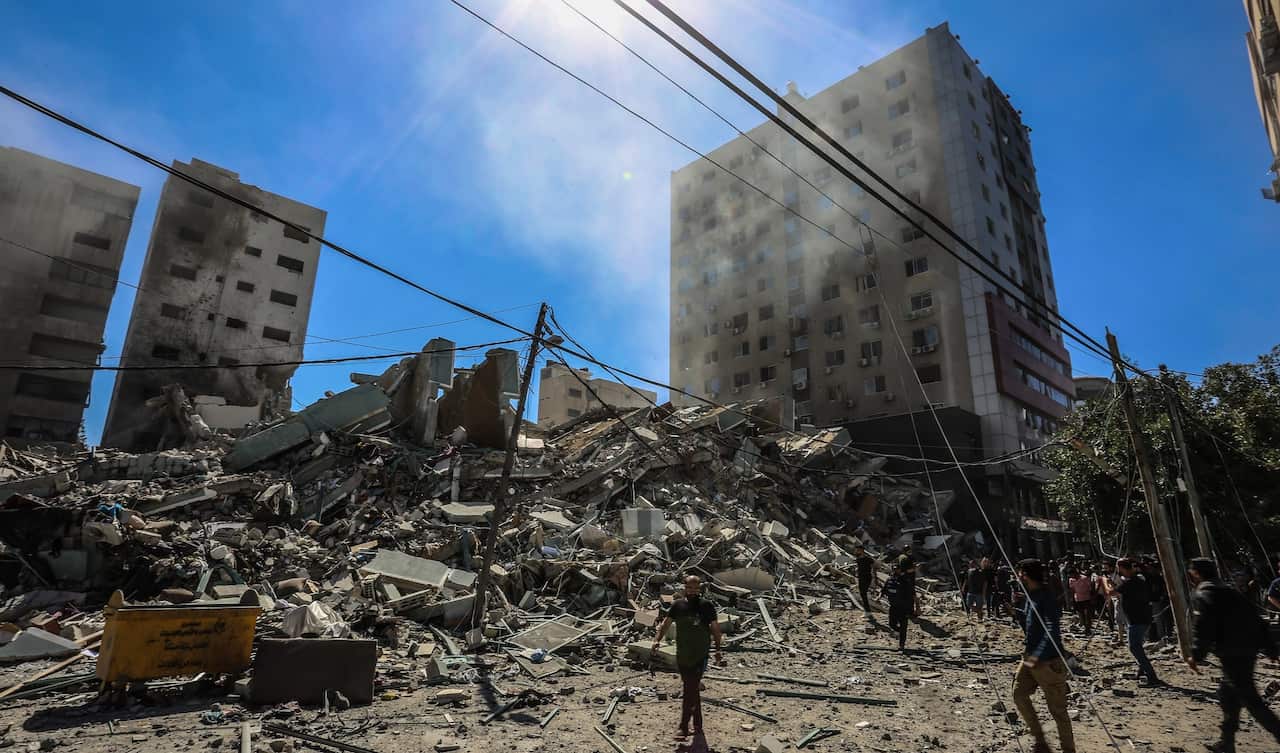 People gather in front of a building that was housing media organisations in Gaza City that was destroyed after Israeli warplanes demolished it.  