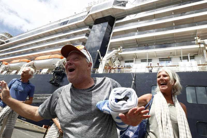 Passengers react after they disembarked from the MS Westerdam, back, at the port of Sihanoukville, Cambodia