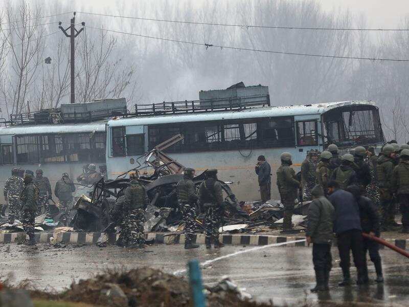 Security forces near the damaged vehicles in Kashmir.