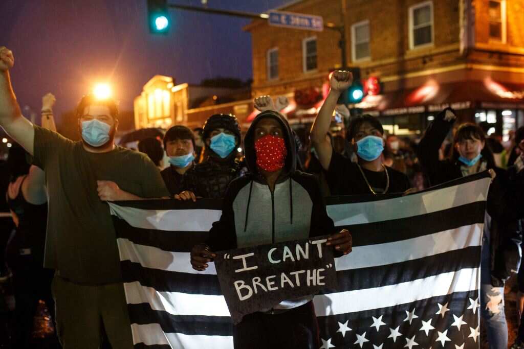 People hold up their fists after protesting near the spot where George Floyd died while in custody.