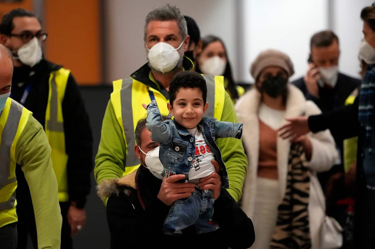 Five-year-old Mustafa is all smiles as his father carries him into their new homeland.