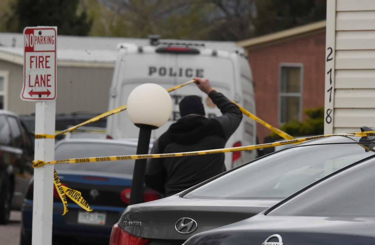 A CSPD officer lifts up crime tape at the scene where seven people were shot and killed early Sunday morning, May 9, 2021 in Colorado Springs, Colorado. 