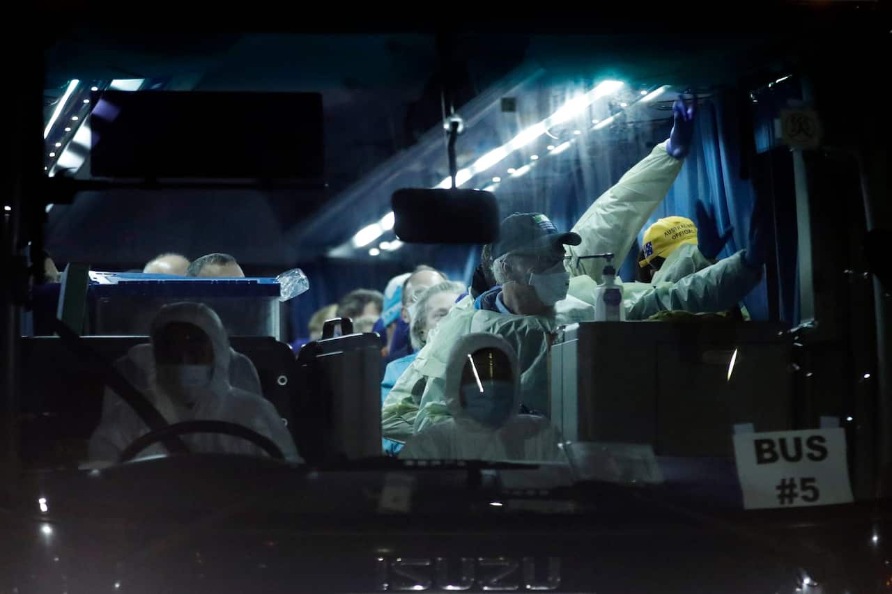 Australian passengers wave after they're disembarked from the quarantined Diamond Princess cruise ship.