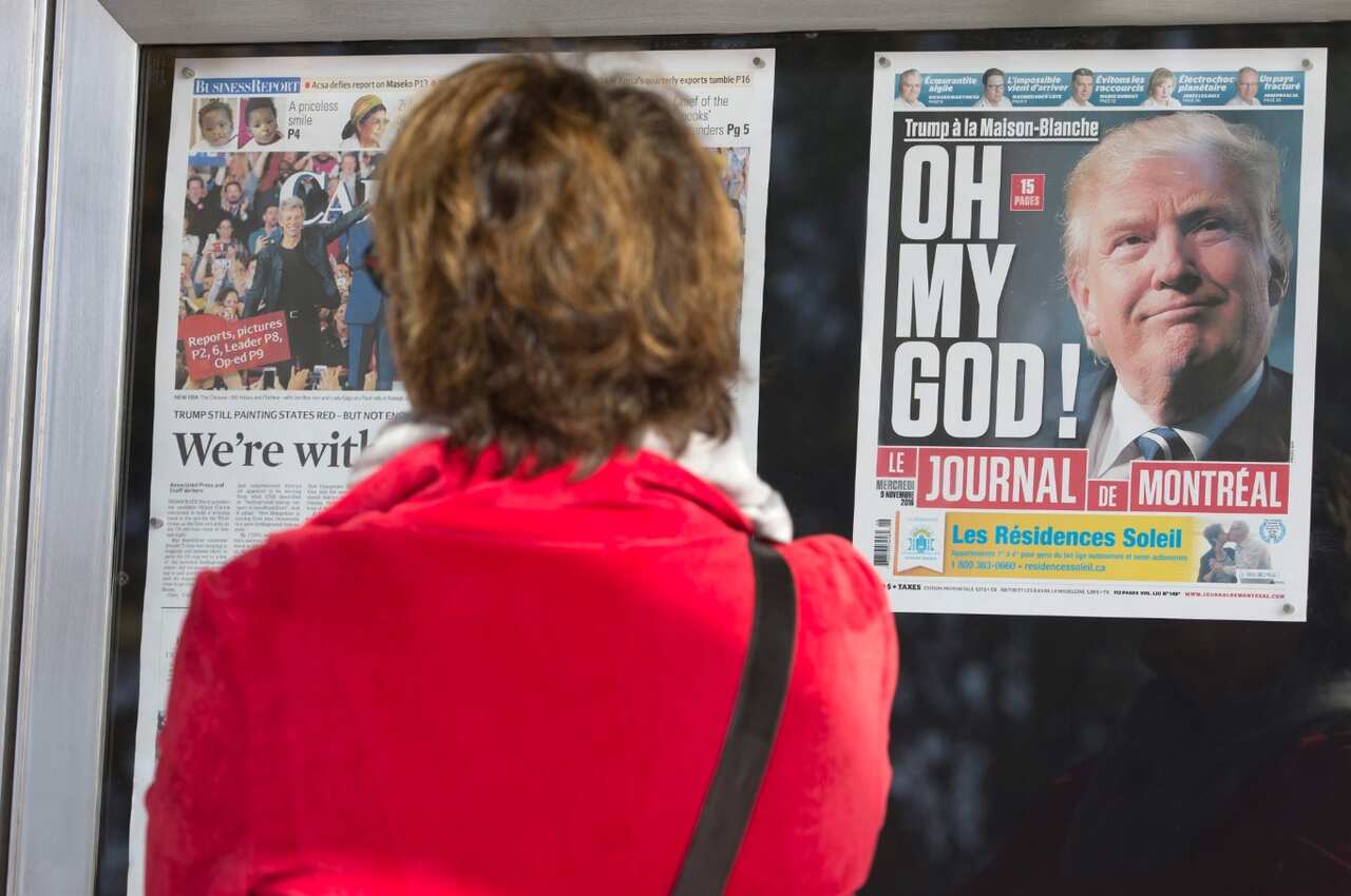 A woman uses her cell phone to take a picture while looking at election coverage on the front page of Canada's Le Journal De Montreal (AAP)