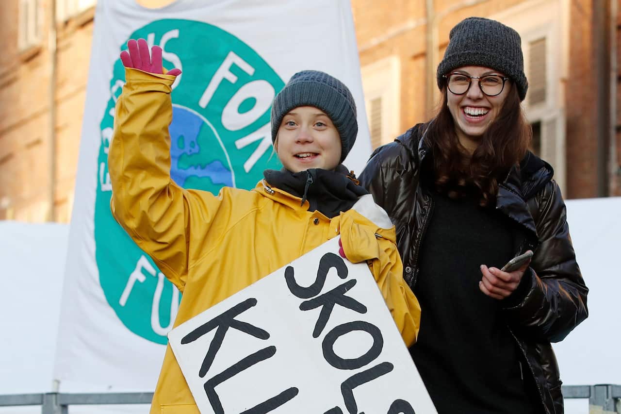 Swedish environmental activist Greta Thunberg holds a sign with writing reading in Swedish "School strike for the climate" as she attends a climate march.