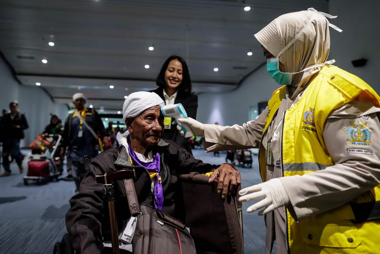 An Indonesian health quarantine official scans the temperature of a passenger upon his arrival at Soekarno-Hatta International Airport in Tangerang, Jakarta.