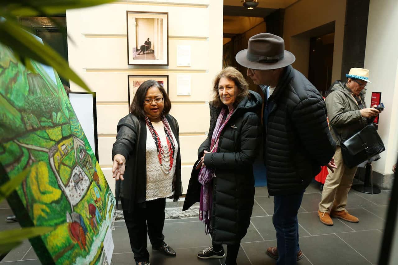 AFCS Project Manager Norminda Forteza showing artwork to some attendees of Serbisyo: Sining at Kwento Exhibit