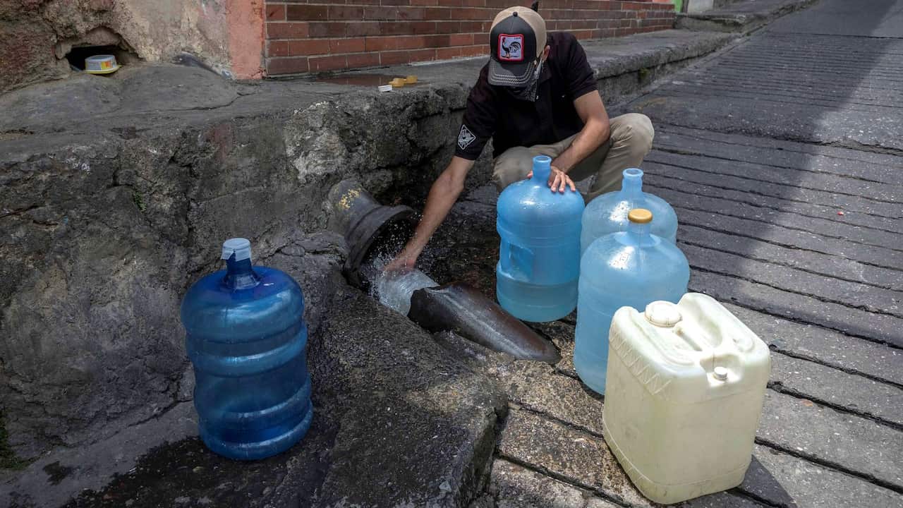 Un hombre recoge agua de una tubería rota en Caracas, Venezuela.
