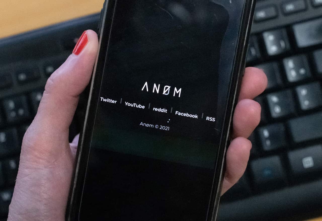 An illustration picture shows the ANoM logo displayed on the screen of an smartphone 