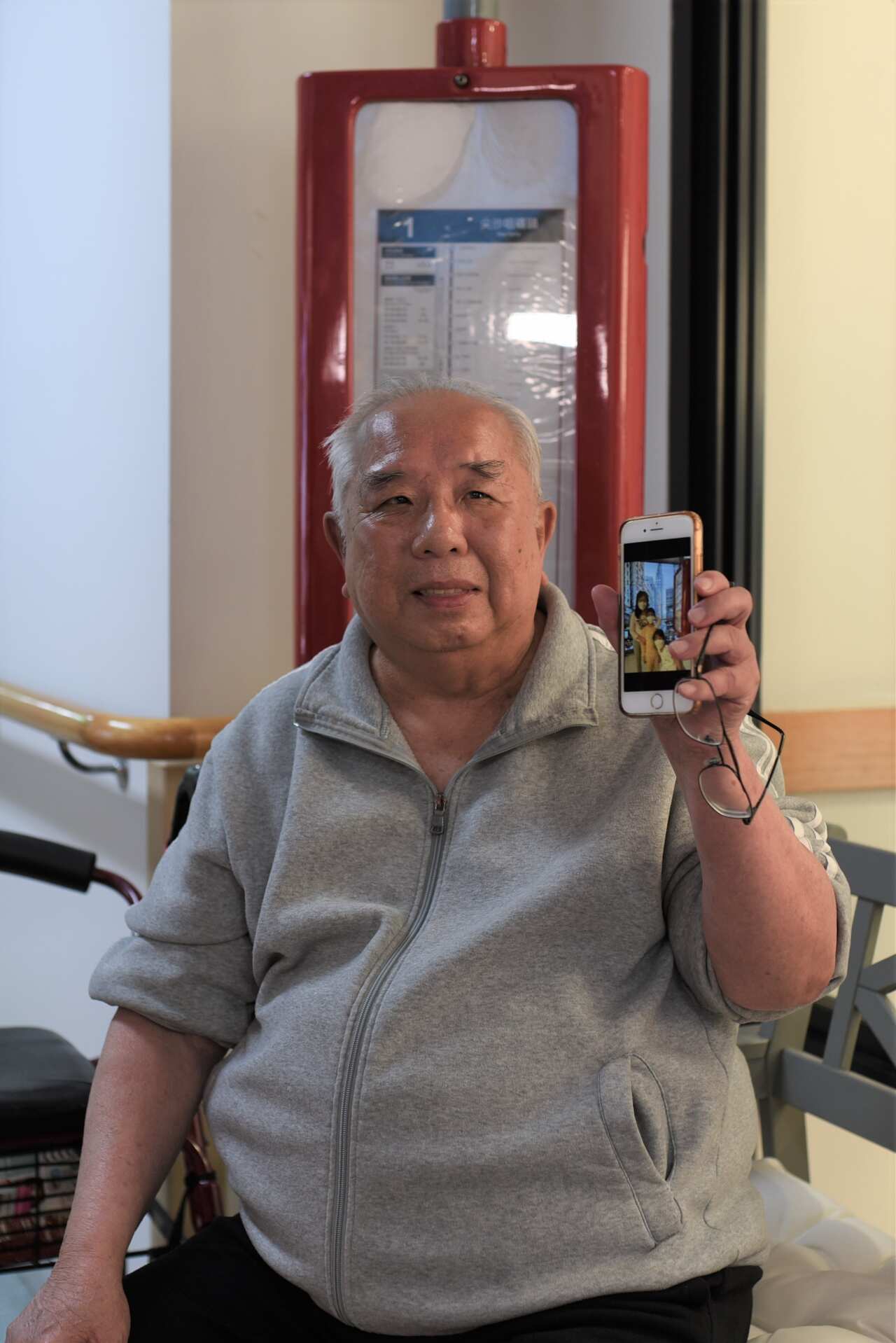 Uncle Fu with photos of his grandchildren at the bus stop.