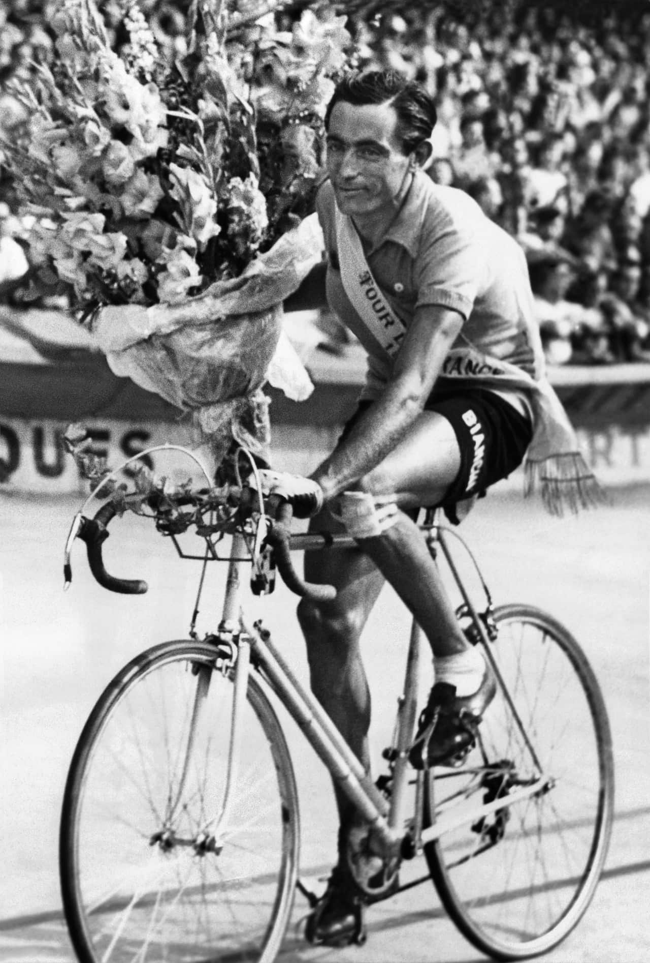 Italian cyclist Fausto Coppi waves to the cheering crowd of spectators on July 24, 1949 in the Parc de Princes stadium in Paris. 
