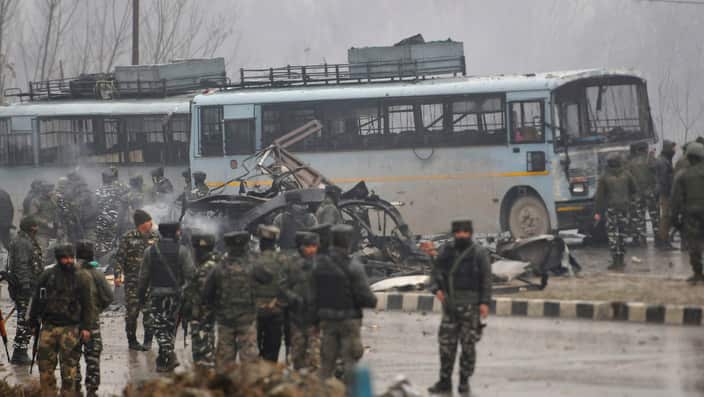 Security forces near the damaged vehicles at Lethpora on the Jammu-Srinagar highway, on February 14, 2019 in Srinagar, India. 
