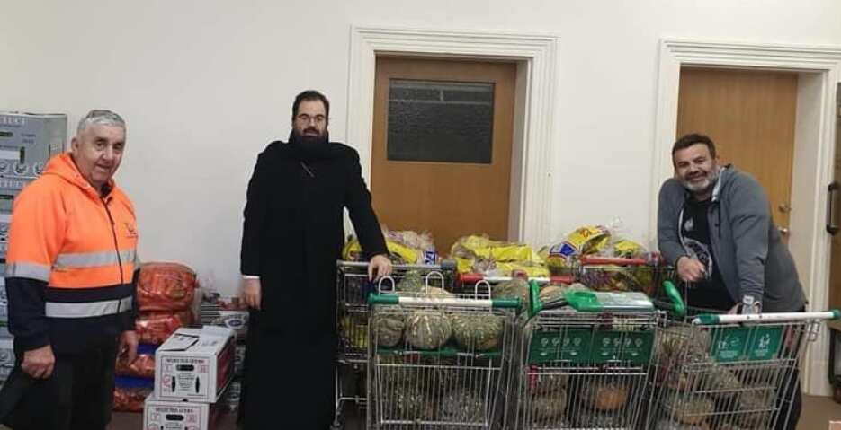 Priest and two volunteers seen alongside collected food donations