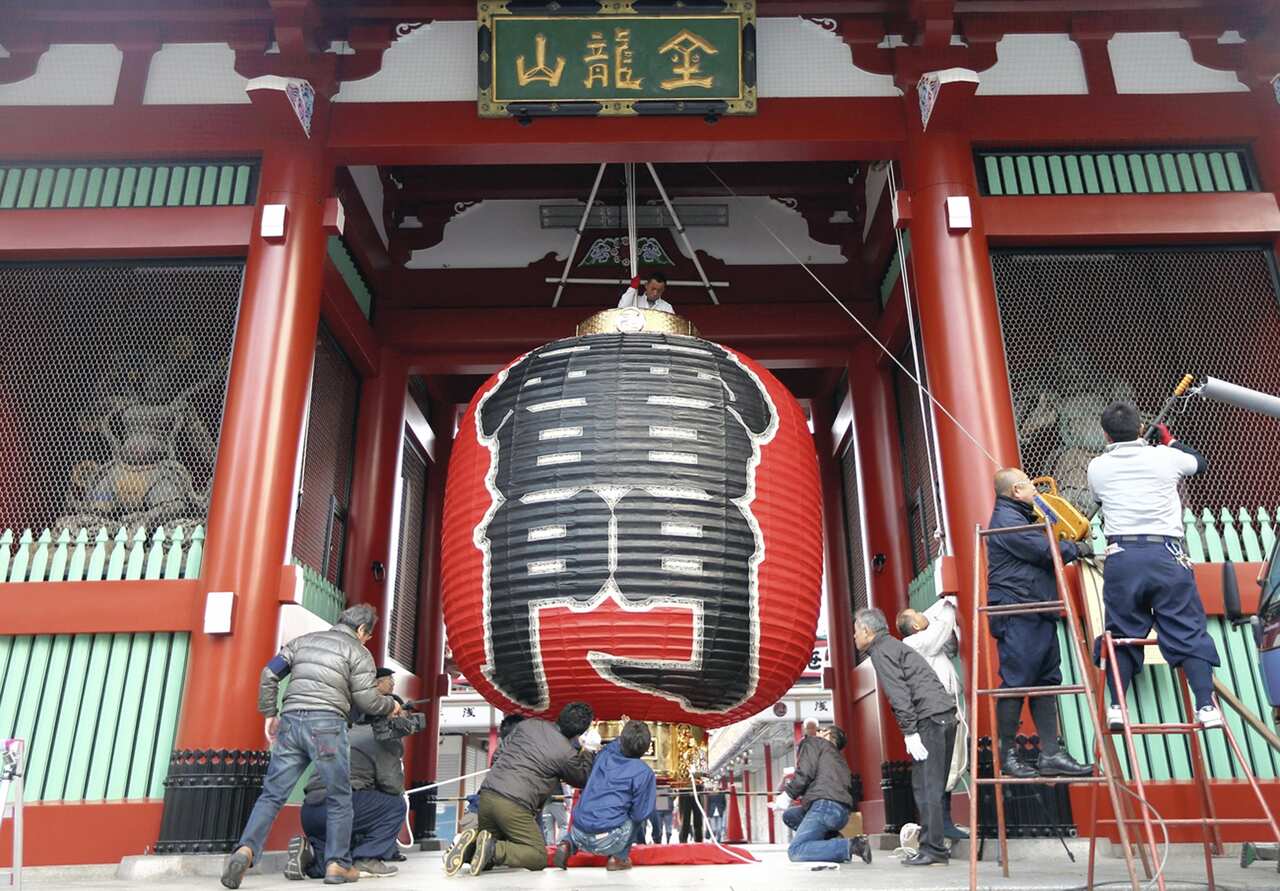 Tourists took photos as the large paper lantern hanging from the Kaminarimon gate of Sensoji temple in Asakusa, Tokyo, is replaced  Monday for the first time in ten years. The new lantern, made of layers of Japanese washi paper over a bamboo frame, is 3.9