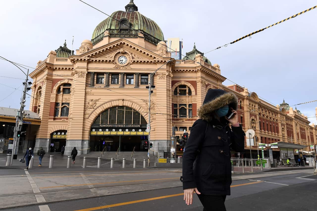 A person wearing a face mask is seen outside of Flinders Street Station in Melbourne.