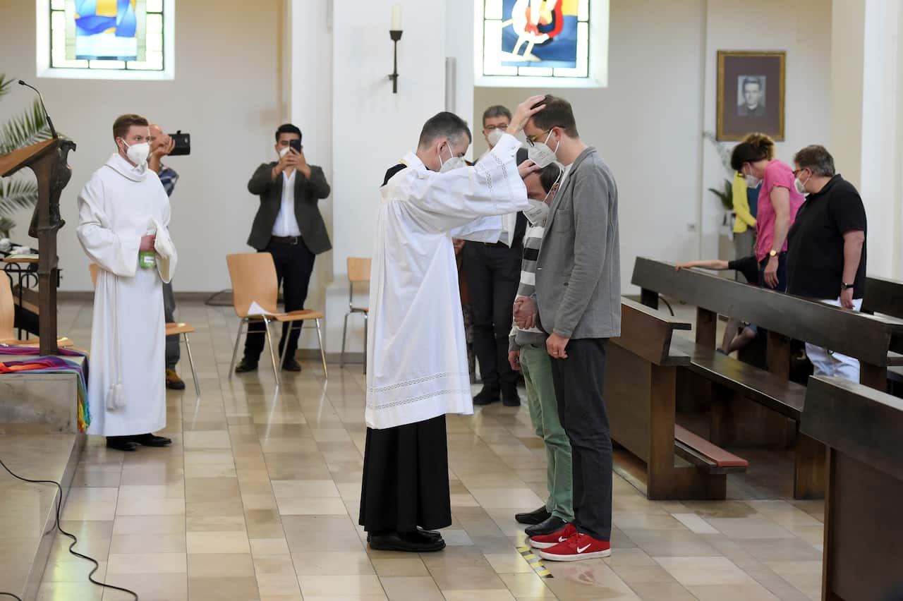 Vicar Wolfgang Rothe, center, blesses two men during a Catholic service with the blessing of same-sex couples in St Benedict's Church in Munich on Sunday.