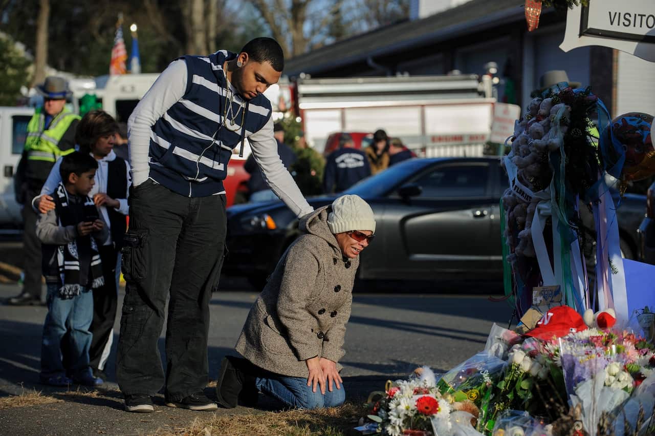 Loved ones visit a memorial for the victims of the Sandy Hook Elementary school a day after the shooting.