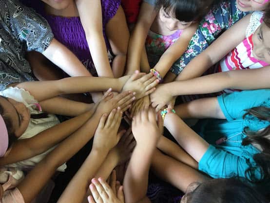 children put their hands in a circle