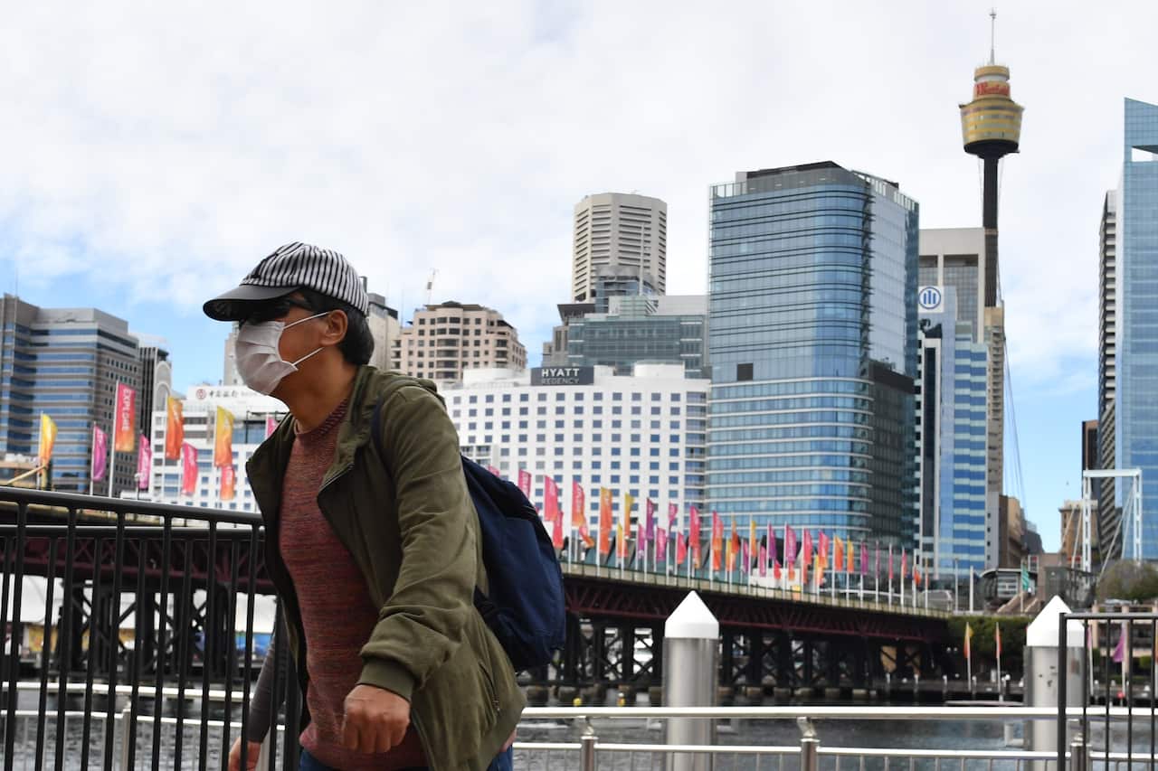 A pedestrian is seen wearing a face mask at Darling Harbour in Sydney, Tuesday, 4 August, 2020. 