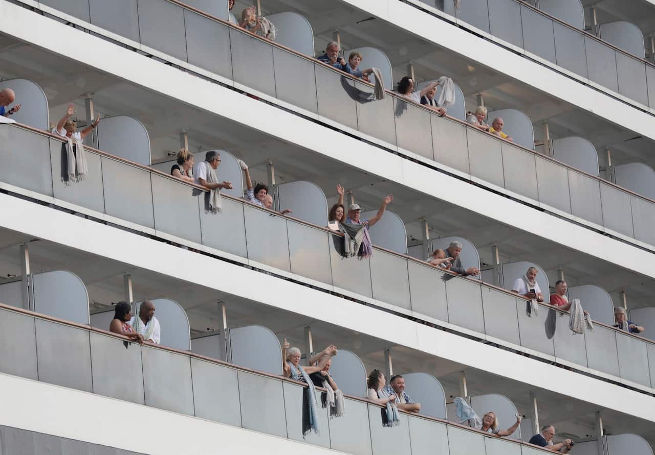 Passengers wave from the MS Westerdam cruise ship at a seaport in Preah Sihanouk province, Cambodia, 14 February 2020. 