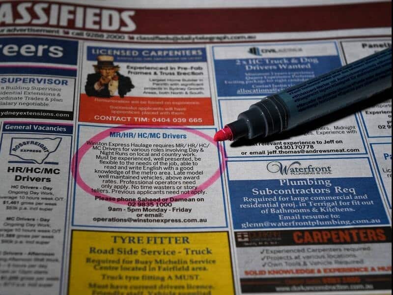 Classified advertisements in a newspaper with a pen circling a job