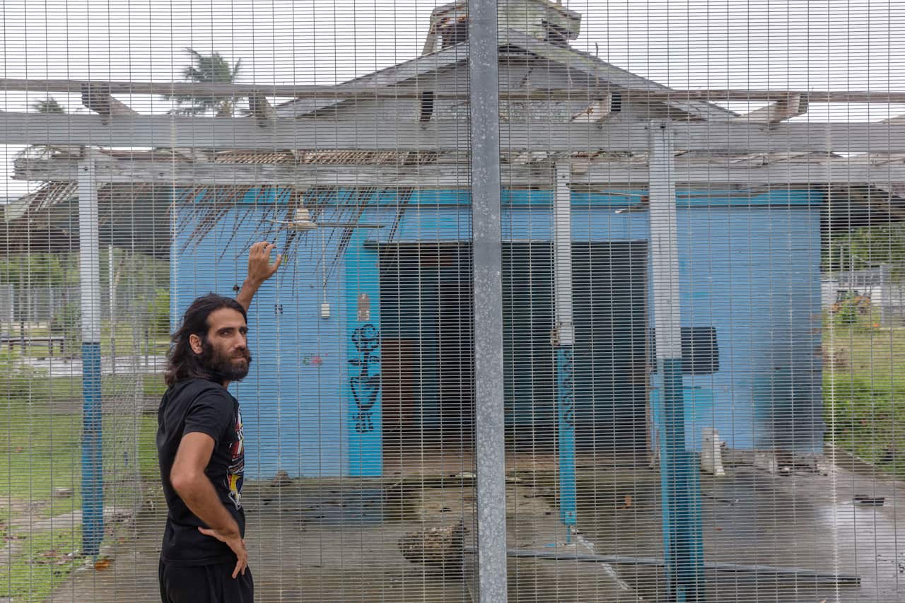 Asylum seeker Behrouz Boochani stands outside the  abandoned naval base on Manus Island where he and others were housed.