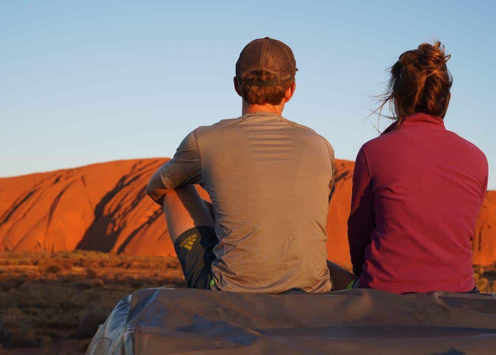 Tourists enjoy Uluru at sunset from a distance.
