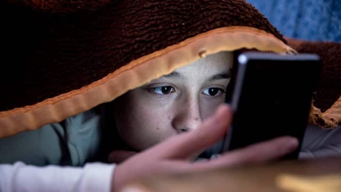 Girl in bed texting on smartphone