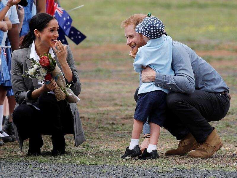 Meghan smiles five-year-old Luke Vincent hugs Prince Harry.