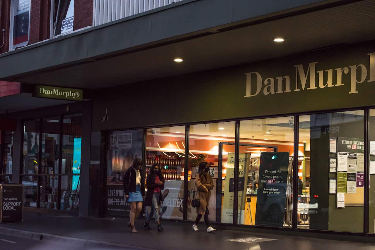 A group of young adults walk by a Dan Murphy's liquor store in Melbourne.