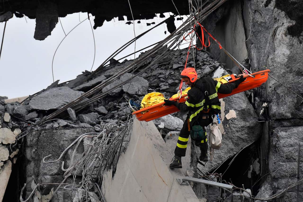 Firefighters rescue a person from the rubble of the collapsed Morandi highway bridge in Genoa, northern Italy, Tuesday, Aug. 14, 2018.