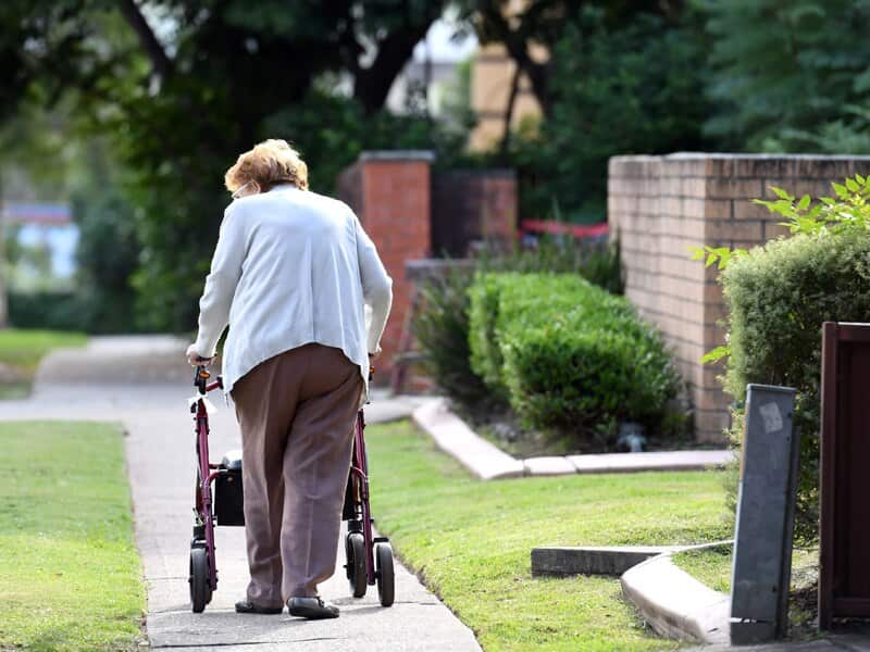 An elderly woman uses a mobility walker