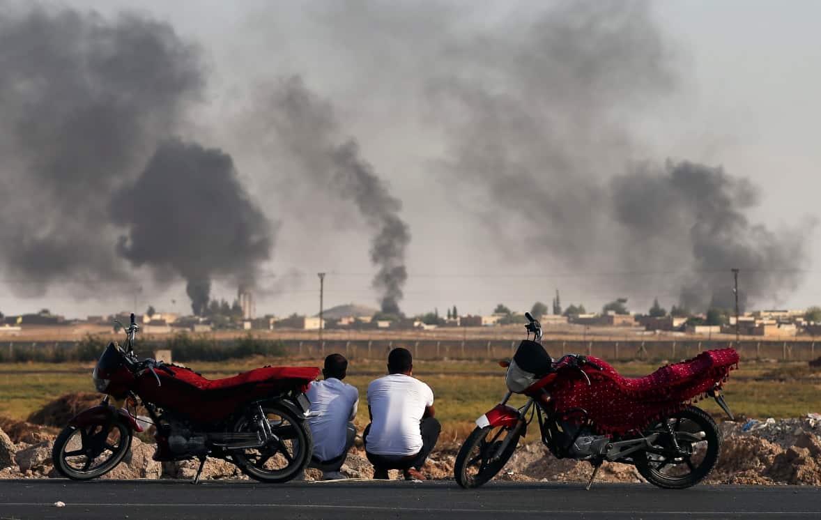 People in southeastern Turkey, at the border with Syria, watch smoke billowing inside Syria 