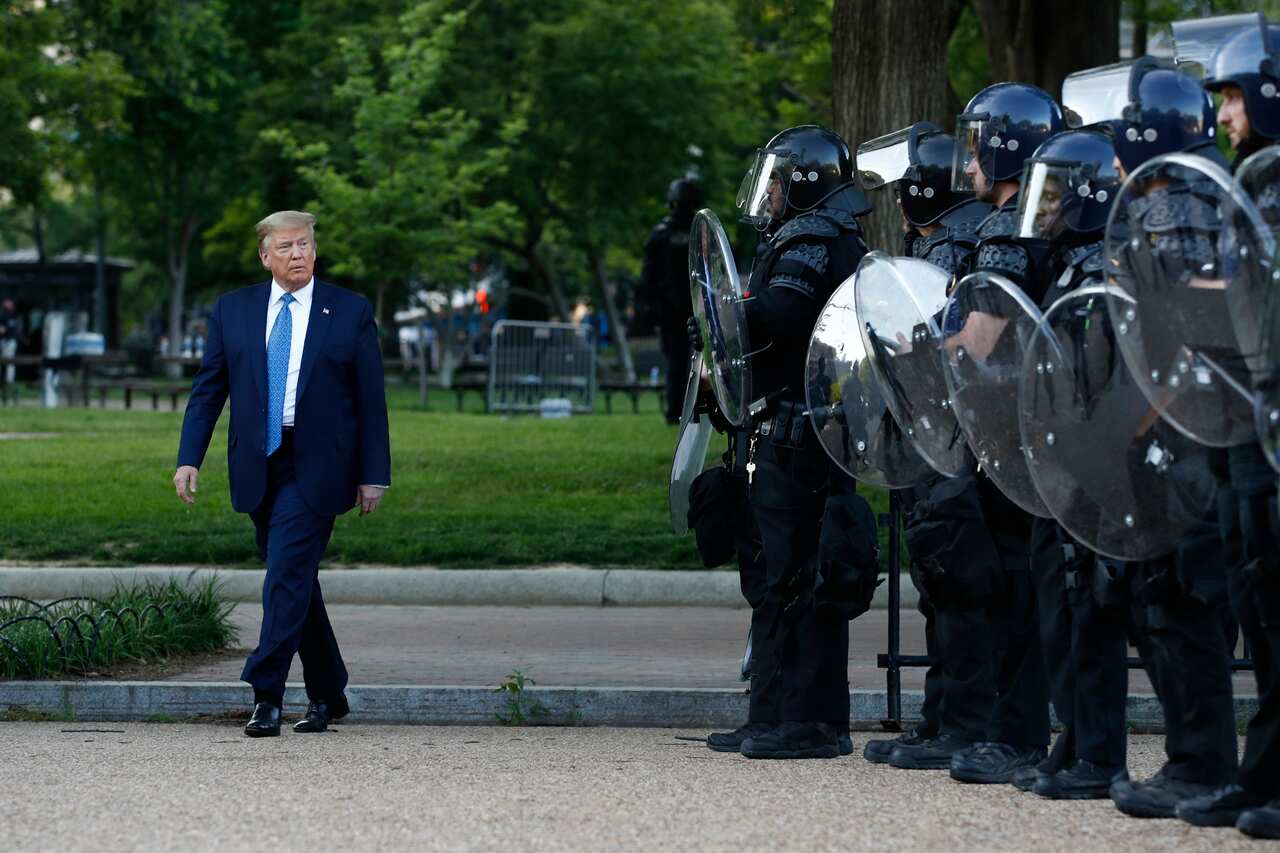 President Donald Trump walks past police in Lafayette Park after visiting outside St. John's Church across from the White House in Washington.