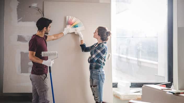 Young couple choosing the right color for their wall while renovating apartment.