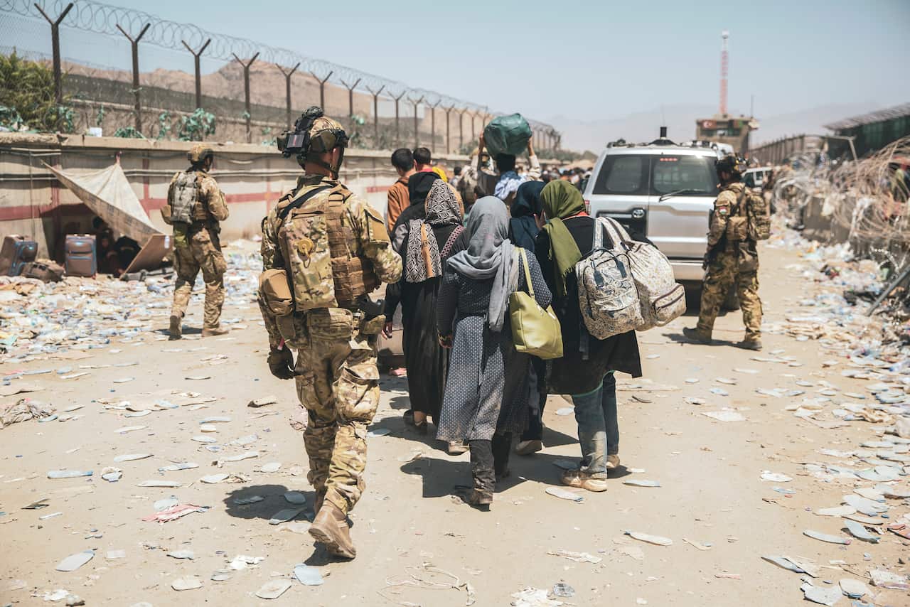 Italian coalition forces assist and escort evacuees for onward processing during an evacuation at Hamid Karzai International Airport in Kabul, Afghanistan, Tuesday, Aug. 24, 2021.