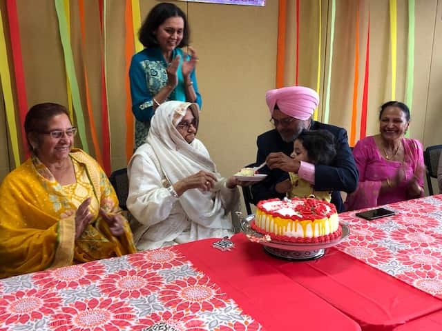 Beeji cutting the celebration cake with her family and friends 