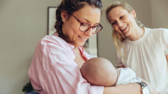 Midwife supporting a breastfeeding mother with her newborn baby