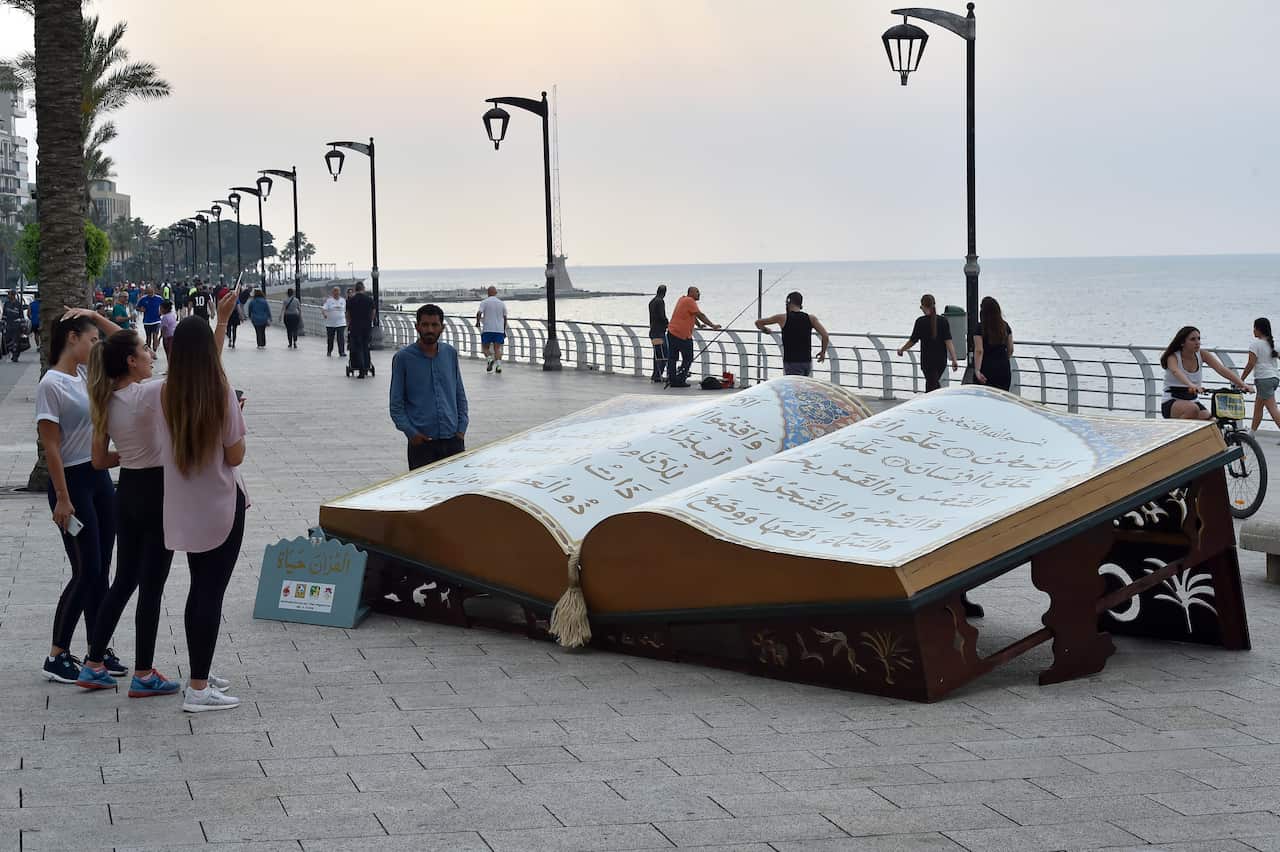 epaselect epa06769314 Girls use their smartphones to take pictures for the huge representation of the holy book of Koran on display during the holy month of Ramadan at the Corniche al-Manara seaside promenade, in Beirut, Lebanon, 28 May 2018. Muslims arou