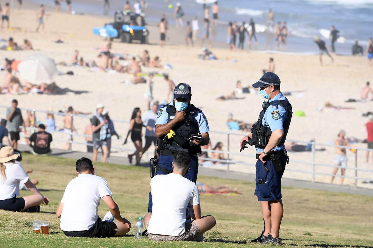 Police speak with two men at Bondi beach, in Sydney, Saturday, September 11, 2021. Greater Sydney and surrounding regions will remain under in lockdown until at least the end of September,