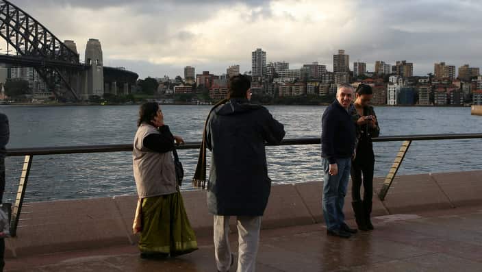 Tourists take pictures of the harbour from the Opera House at Circular Quay in Sydney.