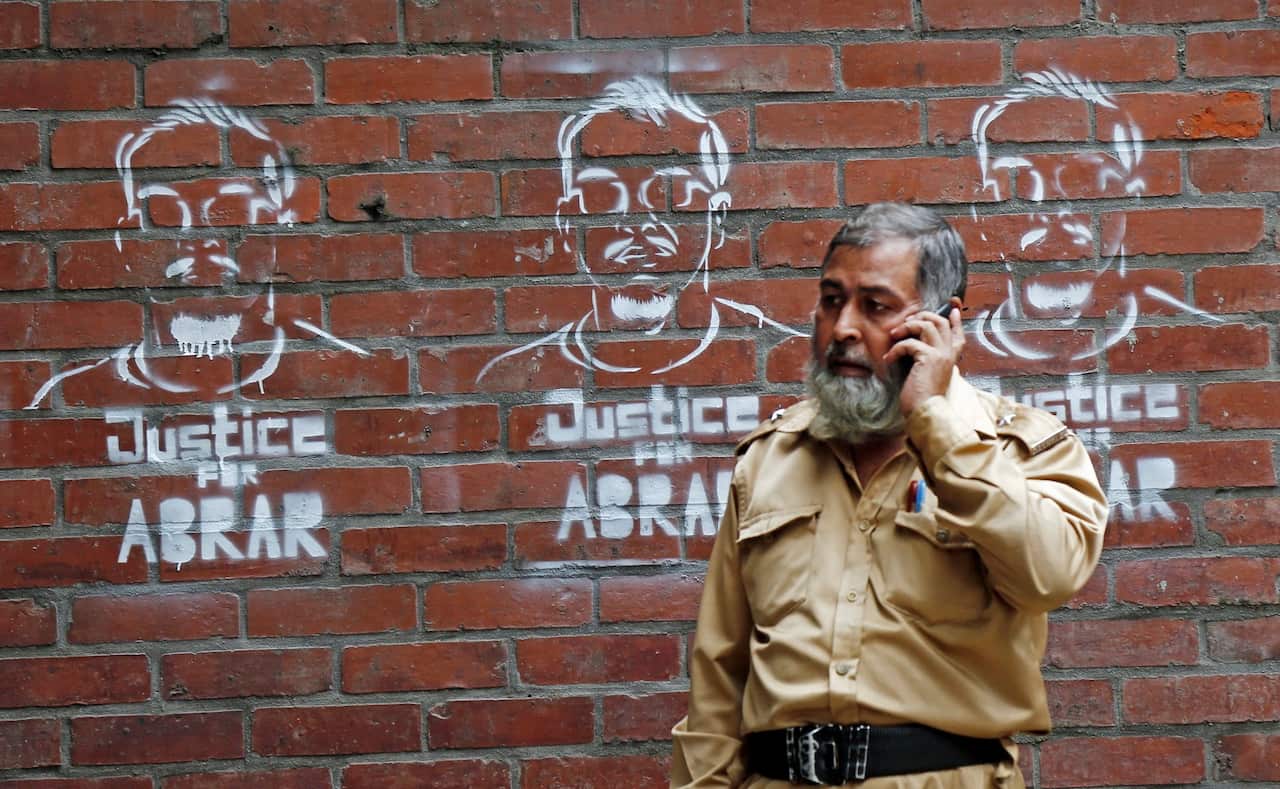 Guard talk his mobile phone next to Abrar graffiti art is seen on the campus wall during the four consecutive days to protest against the murder of Abrar Fahad.