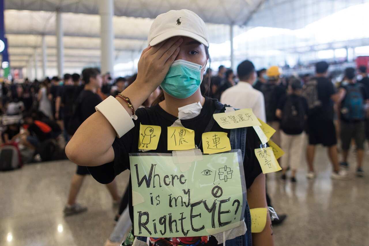 A protester hides her right eye during an occupation of Hong Kong Chek Lap Kok International Airport after a protester was hit with a rubber bullet.