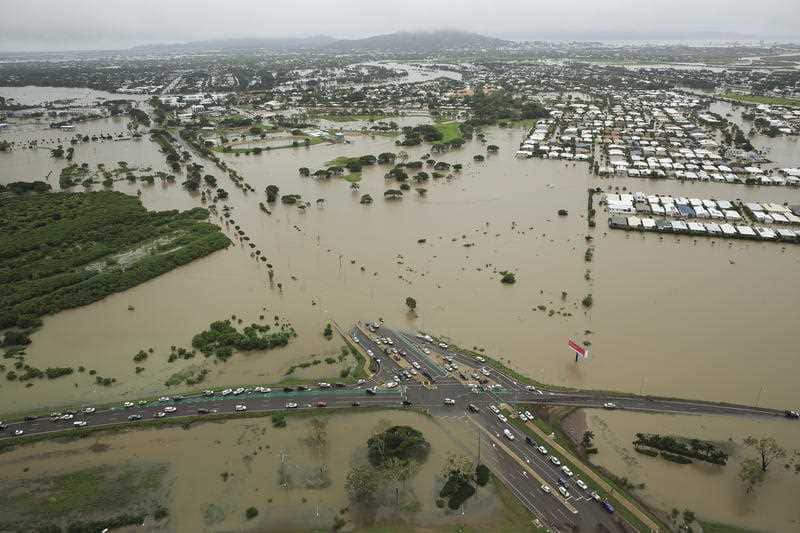 Stranded vehicles are seen from above as floodwater engulfs the intersection of Stuart Drive and the Bruce Highway in Townsville.